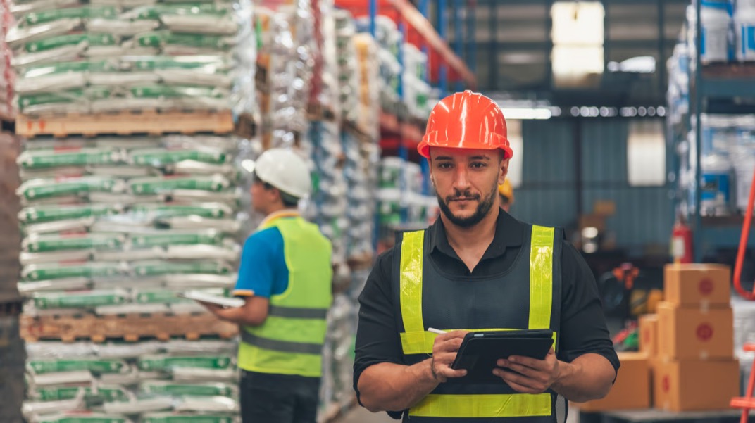 Colaborador de bodega revisando el inventario en una tableta.