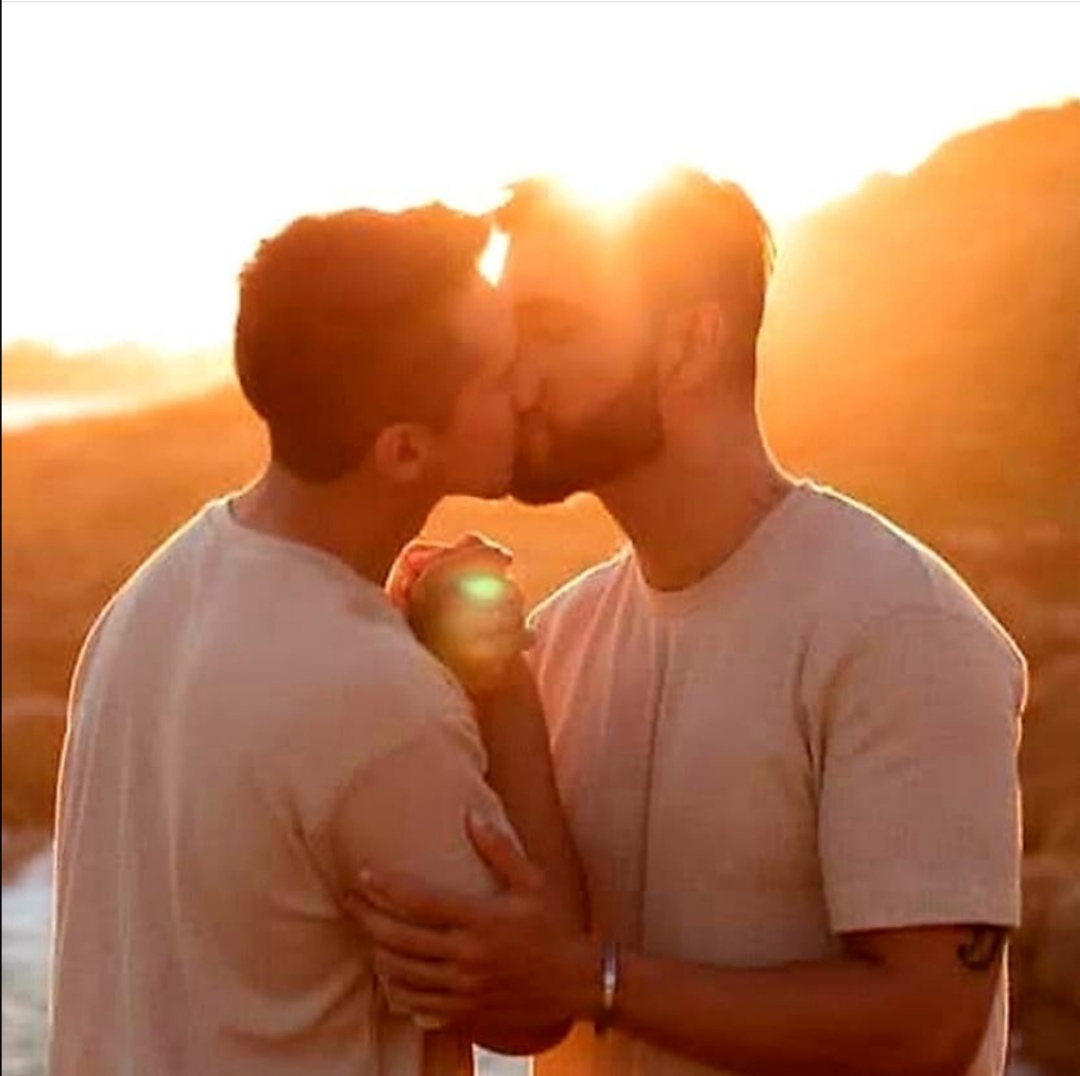 Deux hommes s'embrassent face à un coucher de soleil
