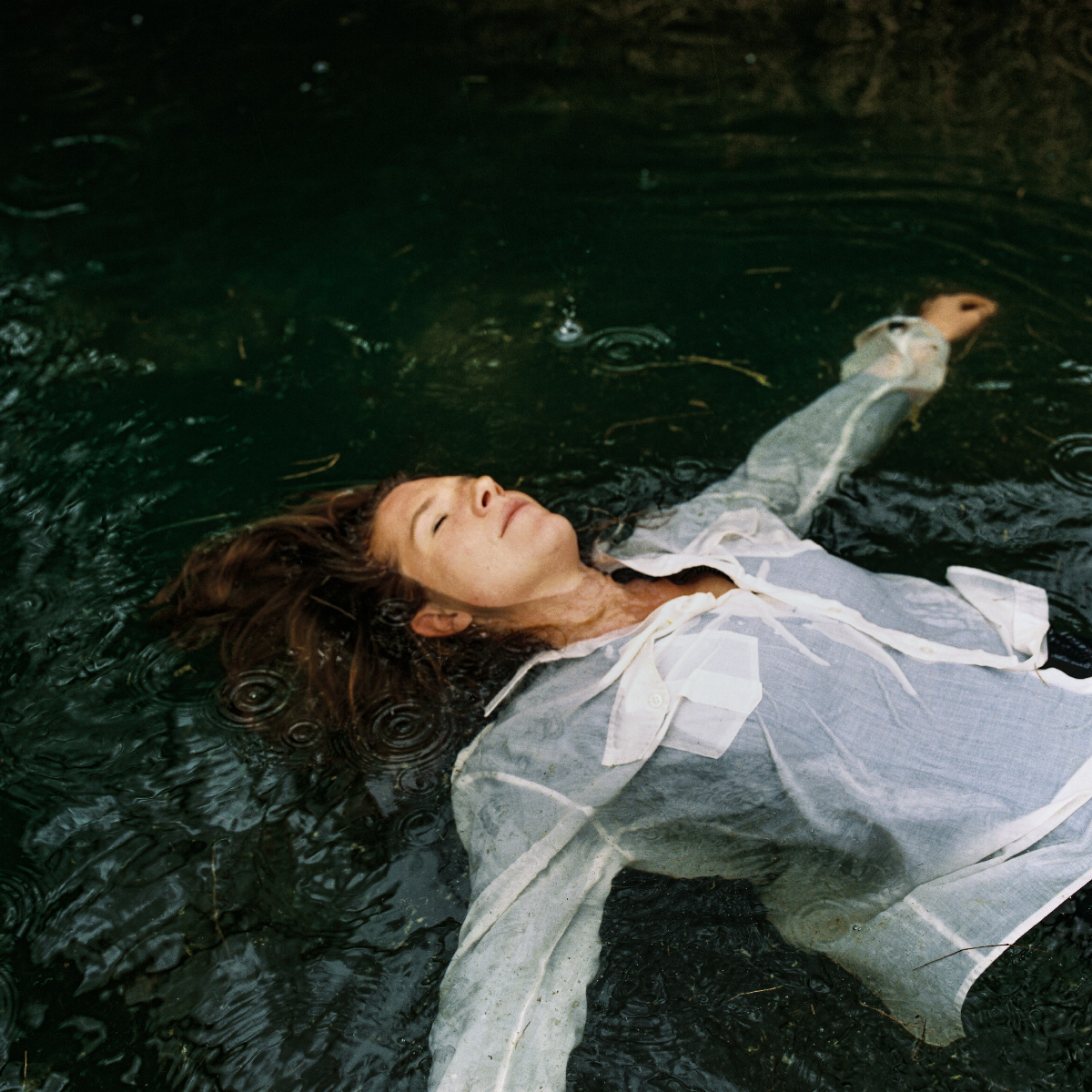 Femme allongée dans l'eau sous la pluie