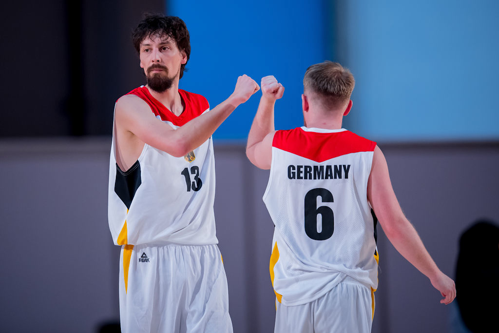 Auf dem Foto sind zwei Basketballspieler, die sich während eines Spiels ihre Fäuste zum Jubel aneinander machen. 