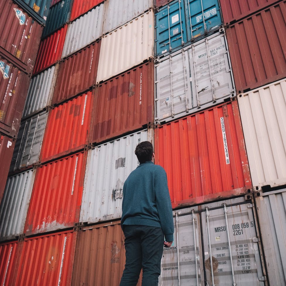 Man looking at shipping containers at a shipyard.