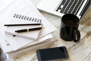 Escriptori amb un ordinador portàtil, llibretes, una tassa i altres elements d'oficina
