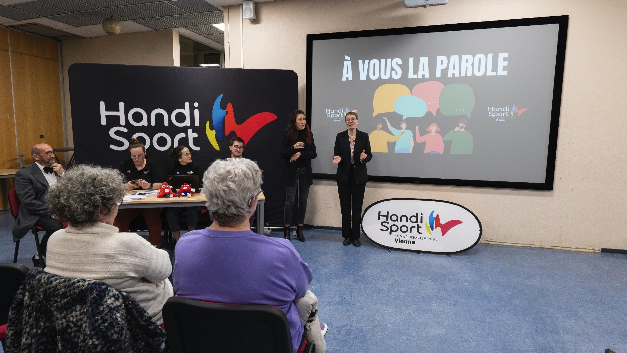 Photo de moi lors de ma prise de parole. A côté de moi, une interprète en LSF