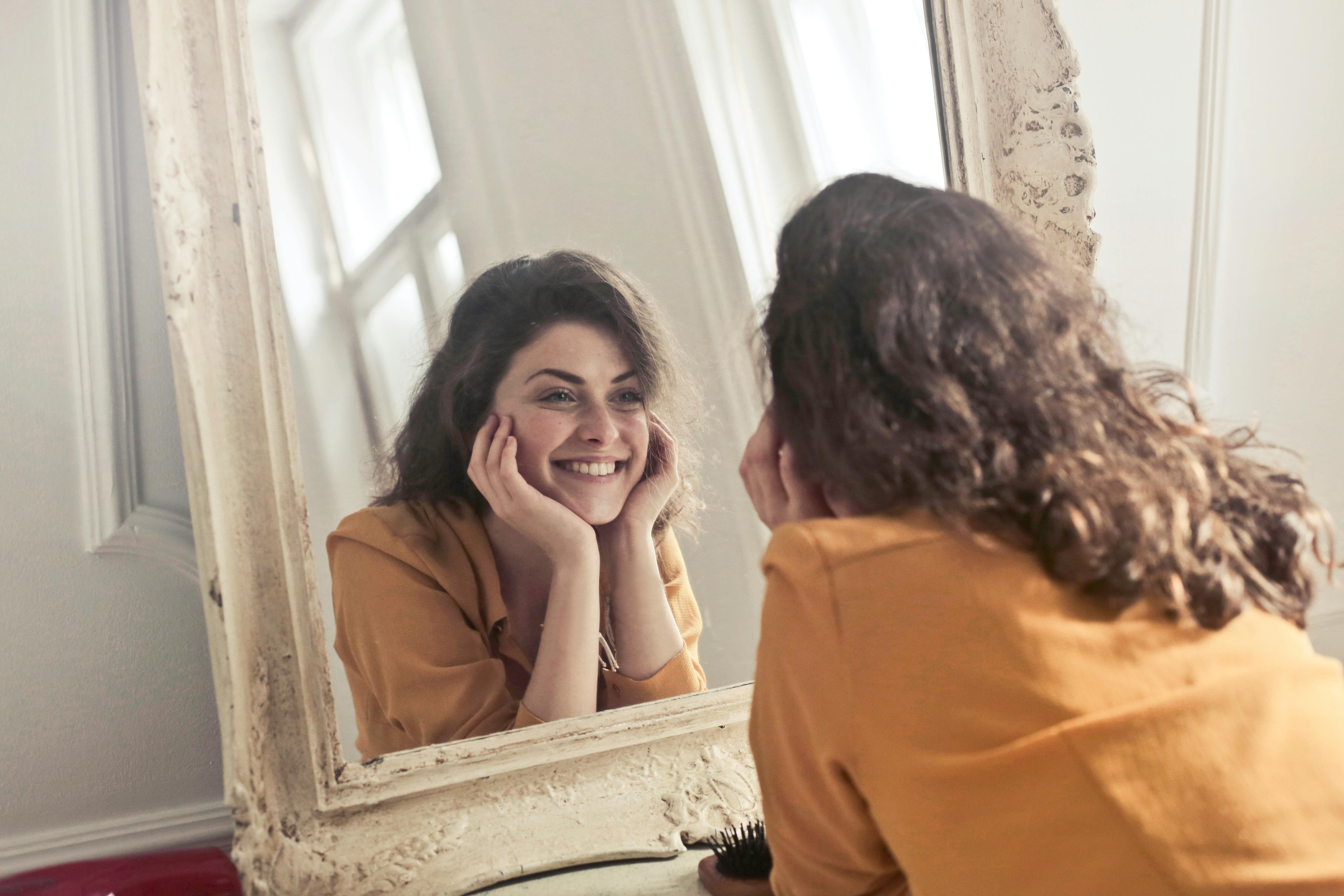 Femme souriante devant un miroir.