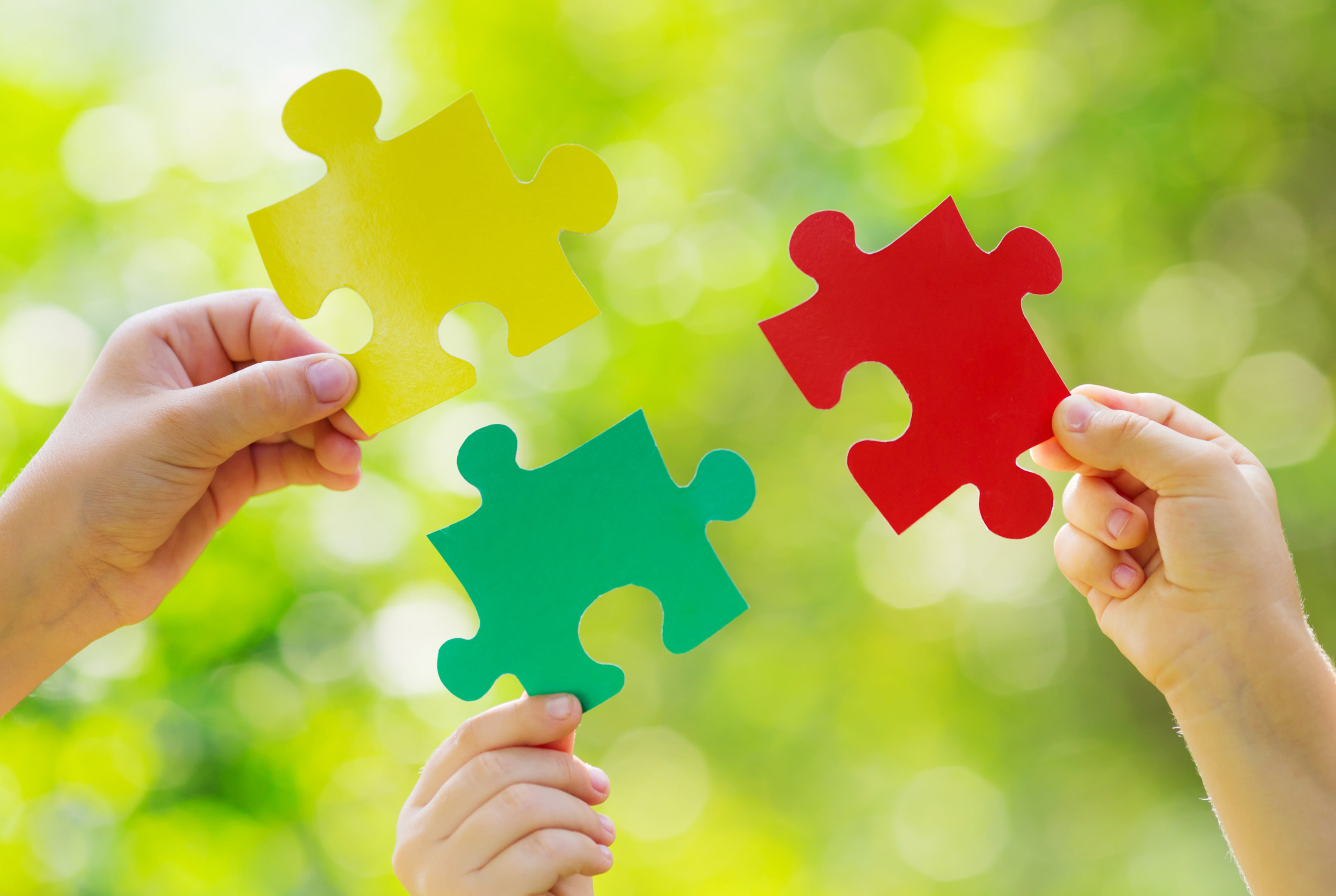 3 Hände, die je ein Puzzleteil in der Hand halten