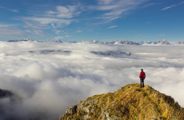 Mann auf Berggipfel über Wolken