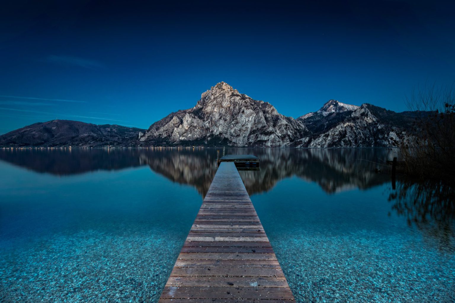 Blauer See, Steg und Berge im Hintergrund
