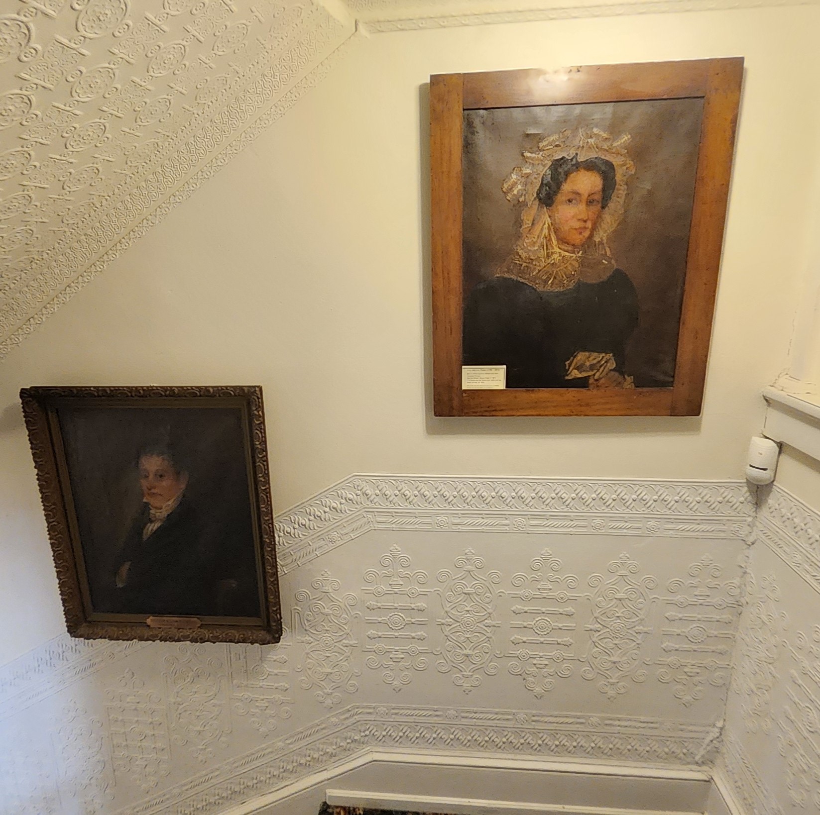 Portraits of William Potter (left) and Lucy Winters Potter (right) on a wall inside the Miles-Humes House. The wall is leading up to the second landing of the main staircase.