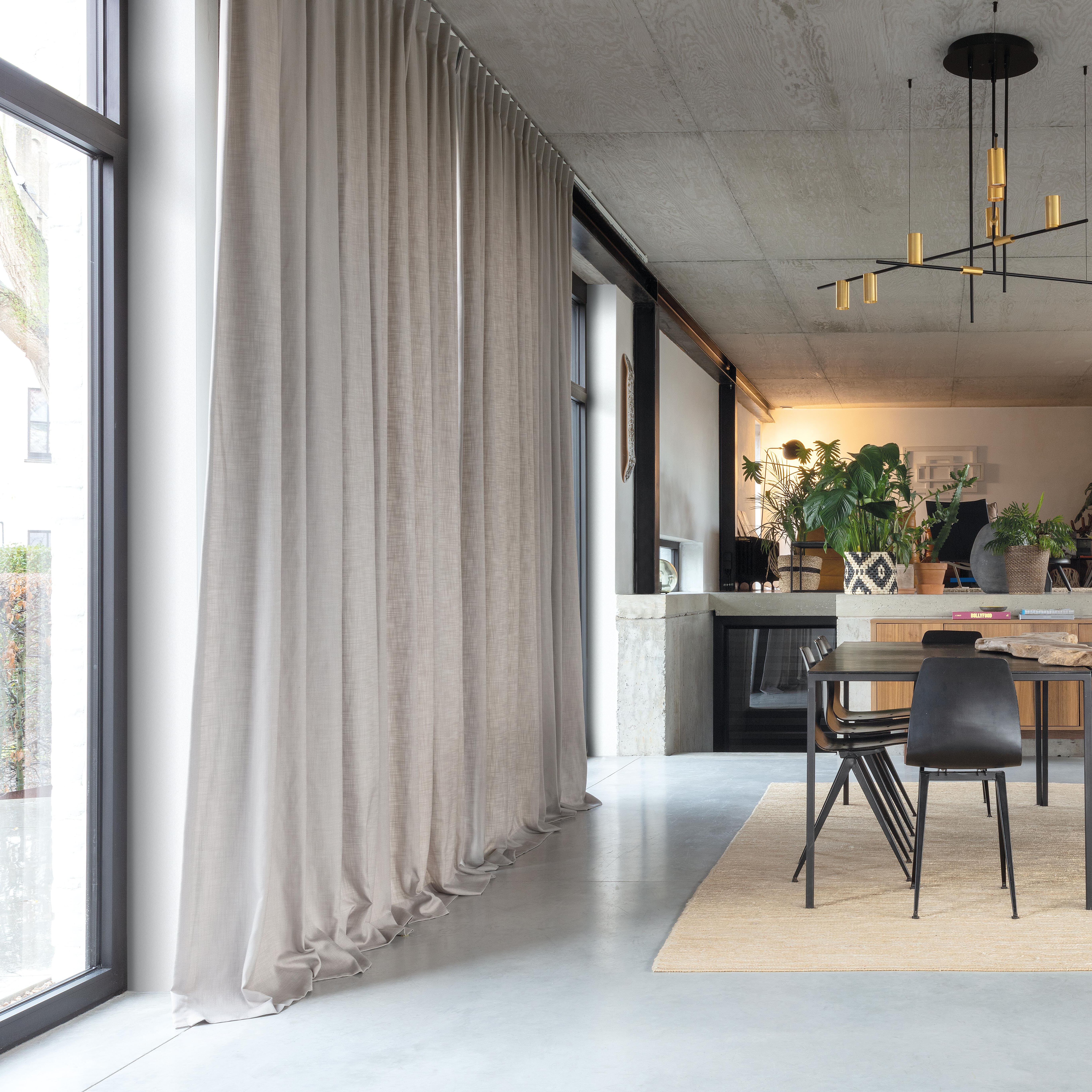 Floor-to-ceiling beige curtains in a modern open-plan interior, demonstrating our expert curtain service for contemporary homes.